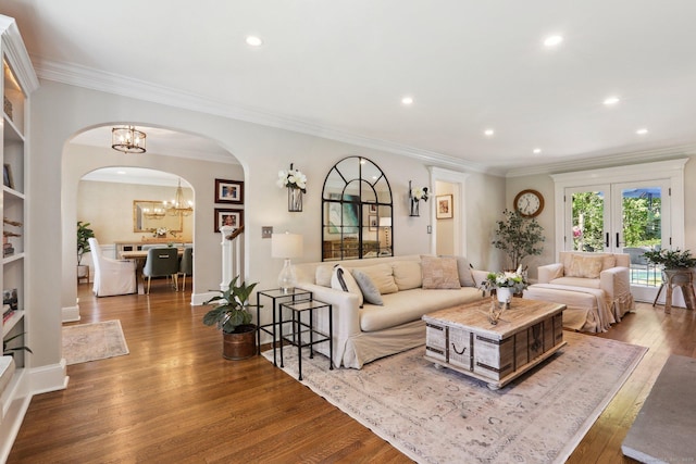 living area with arched walkways, recessed lighting, wood finished floors, and an inviting chandelier
