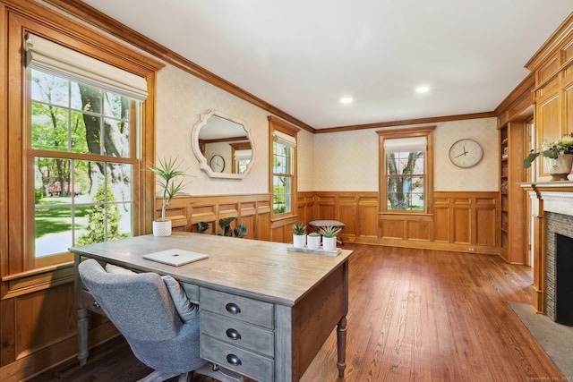 home office with dark wood-style flooring, a fireplace with flush hearth, a wainscoted wall, ornamental molding, and recessed lighting