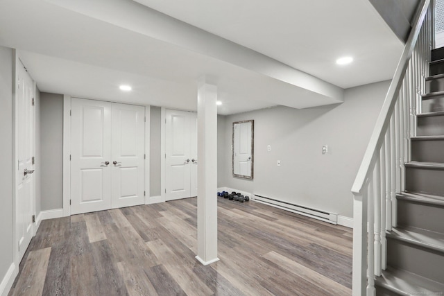 finished below grade area featuring baseboard heating, stairs, recessed lighting, baseboards, and wood finished floors