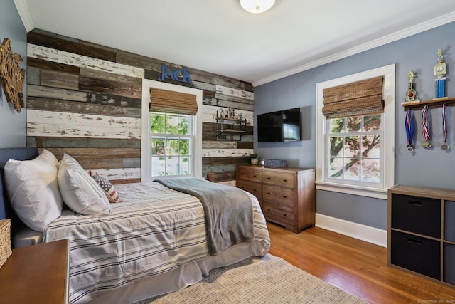 bedroom featuring wooden walls, baseboards, multiple windows, and wood finished floors