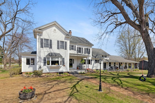 rear view of house featuring covered porch, a lawn, a chimney, and roof with shingles