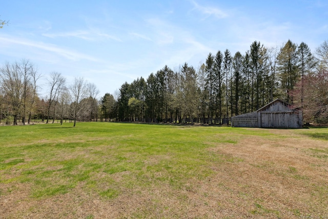view of yard featuring a forest view, a pole building, and an outdoor structure