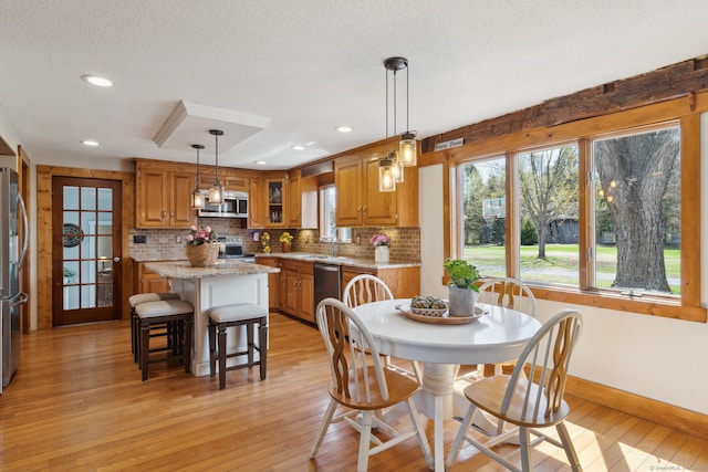dining space with a textured ceiling, baseboards, a wealth of natural light, and light wood-style floors