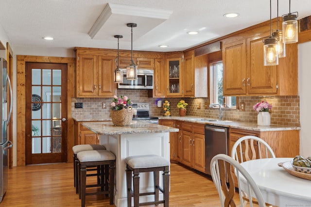 kitchen with a sink, appliances with stainless steel finishes, light wood-type flooring, and brown cabinets
