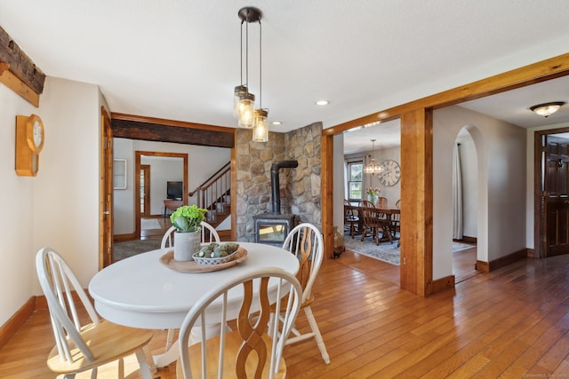 dining space featuring a notable chandelier, a wood stove, light wood-style flooring, recessed lighting, and baseboards
