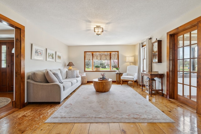 living area with a textured ceiling, a healthy amount of sunlight, and hardwood / wood-style flooring