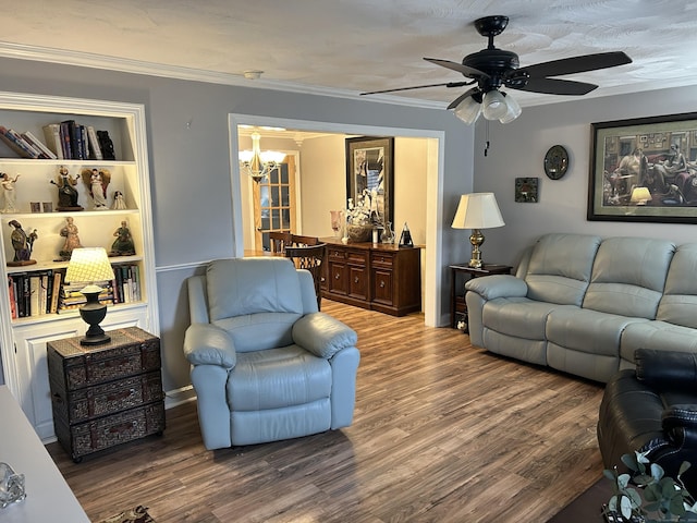 living area with wood finished floors, ceiling fan with notable chandelier, and ornamental molding