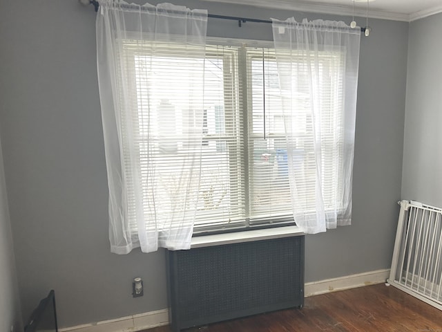 spare room with radiator heating unit, dark wood-style flooring, baseboards, and crown molding