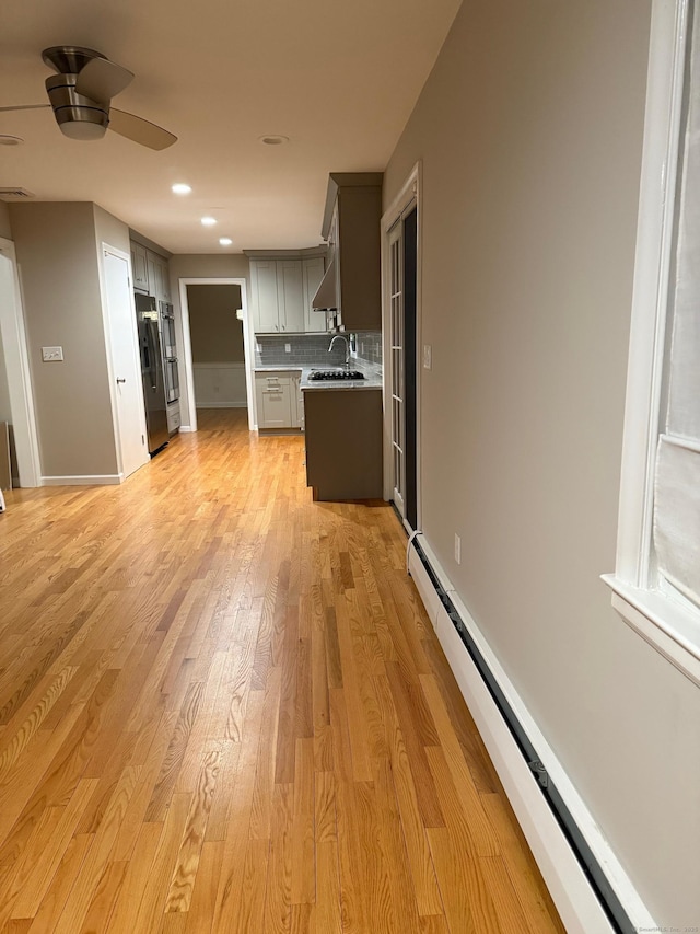 kitchen with fridge with ice dispenser, a sink, gray cabinets, backsplash, and a baseboard heating unit