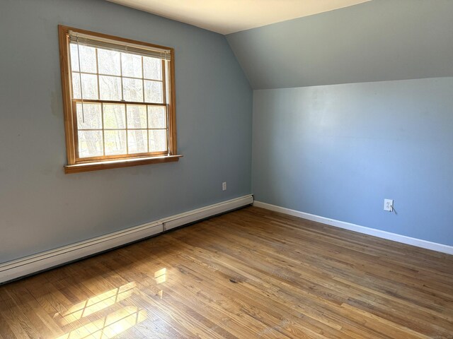 additional living space featuring baseboards, wood finished floors, vaulted ceiling, and baseboard heating
