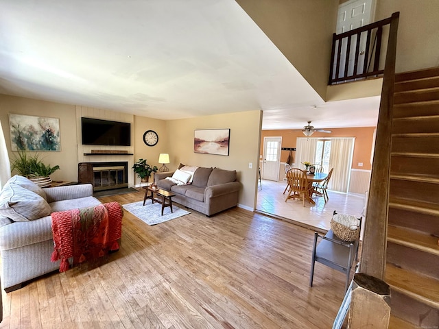 living room featuring stairs, light wood-style floors, and a glass covered fireplace
