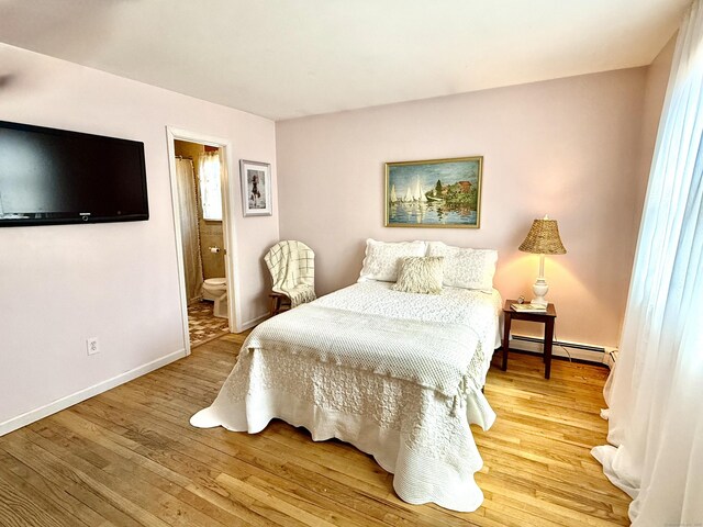 bedroom with baseboards, connected bathroom, wood finished floors, and baseboard heating