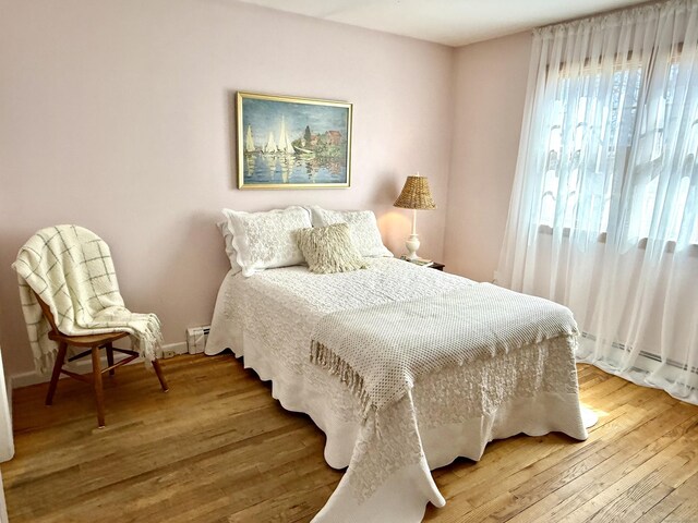 bedroom with light wood finished floors, baseboards, and baseboard heating