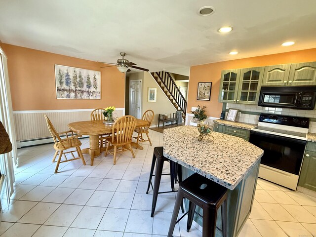 kitchen featuring a kitchen bar, light tile patterned floors, white electric range oven, a ceiling fan, and black microwave