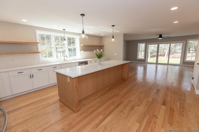 58 Killingworth Tpke, Clinton, CT 06413 - kitchen with open shelves, stainless steel dishwasher, a kitchen island, a sink, and light wood finished floors