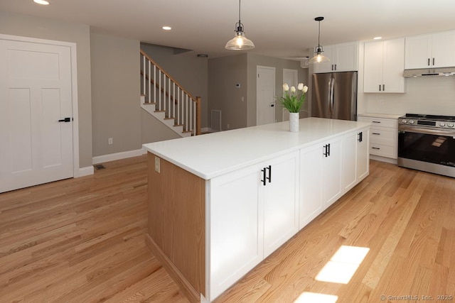 58 Killingworth Tpke, Clinton, CT 06413 - kitchen with white cabinetry, a center island, stainless steel appliances, under cabinet range hood, and light wood finished floors