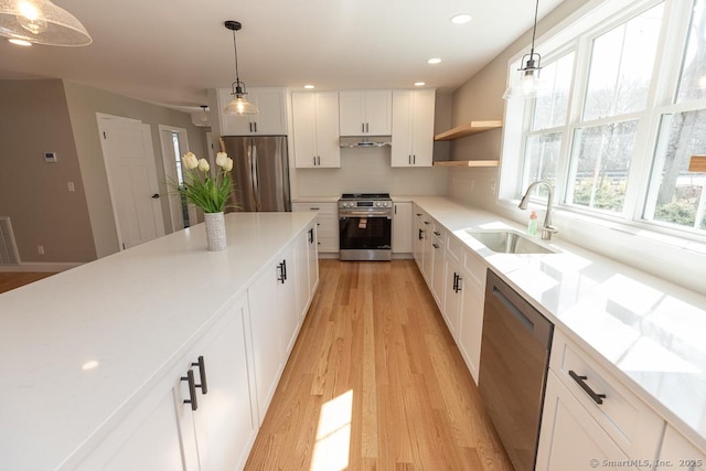 58 Killingworth Tpke, Clinton, CT 06413 - kitchen with white cabinets, light wood finished floors, stainless steel appliances, under cabinet range hood, and a sink