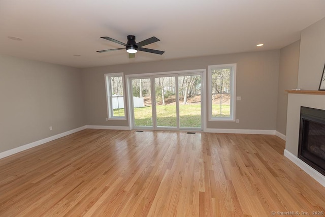 58 Killingworth Tpke, Clinton, CT 06413 - unfurnished living room featuring a glass covered fireplace, baseboards, and a wealth of natural light