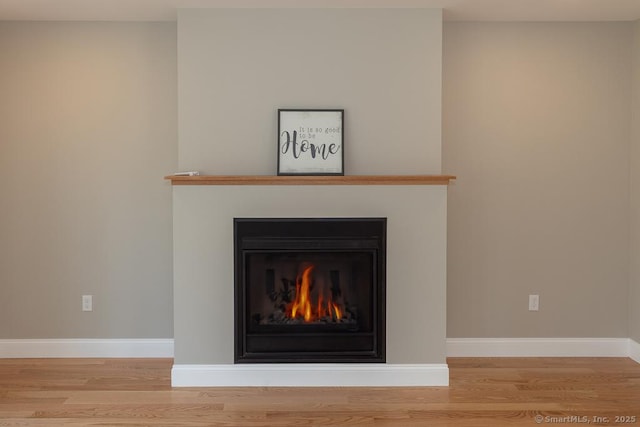 58 Killingworth Tpke, Clinton, CT 06413 - details featuring baseboards, a warm lit fireplace, and wood finished floors