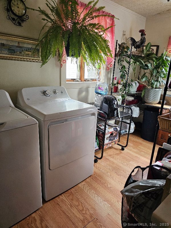125 Mckinley Ave, Norwich, CT 06360 - clothes washing area featuring washing machine and dryer, wood finished floors, laundry area, and crown molding