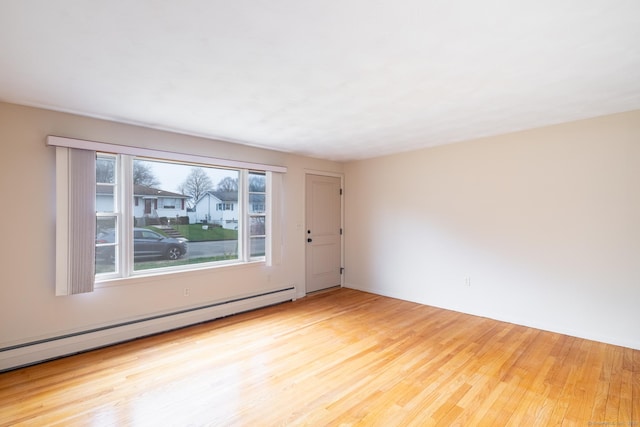unfurnished room with a baseboard radiator and wood finished floors