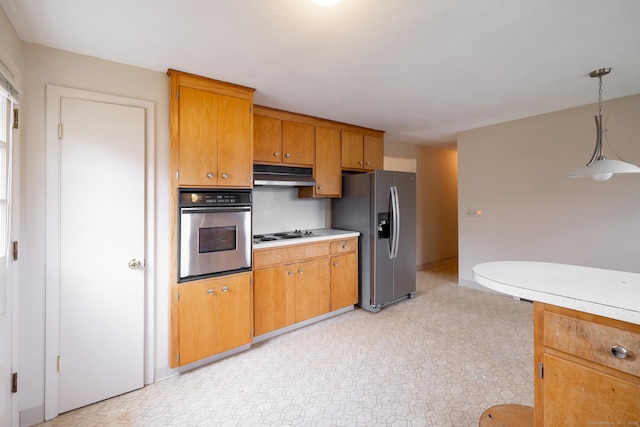 kitchen featuring brown cabinets, appliances with stainless steel finishes, light countertops, under cabinet range hood, and hanging light fixtures