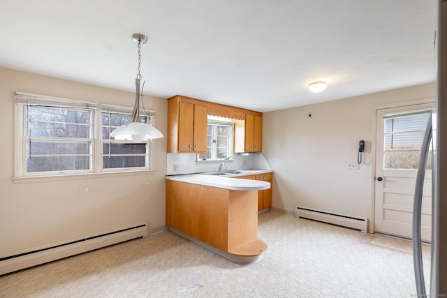 kitchen featuring brown cabinetry, a baseboard heating unit, a peninsula, and light countertops