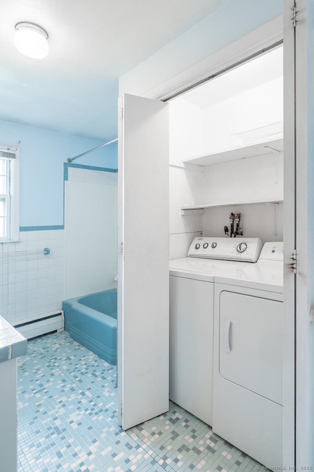 washroom featuring laundry area, wainscoting, baseboard heating, tile walls, and washer and clothes dryer