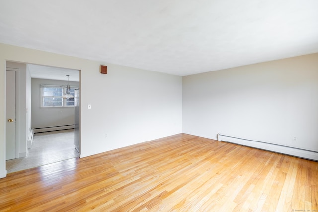empty room with a baseboard heating unit, light wood finished floors, and a baseboard radiator