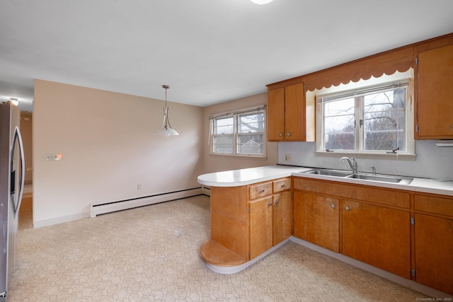 kitchen featuring a baseboard radiator, a peninsula, light countertops, and a sink