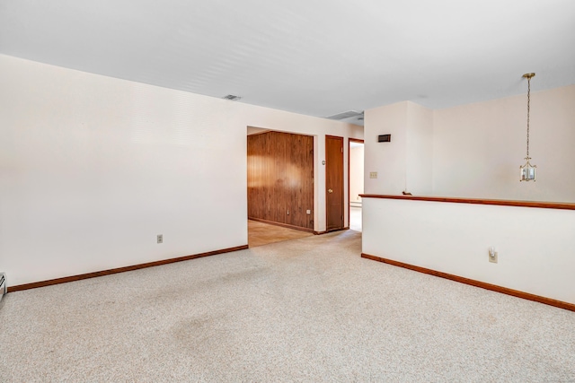 empty room with baseboards, visible vents, and light carpet