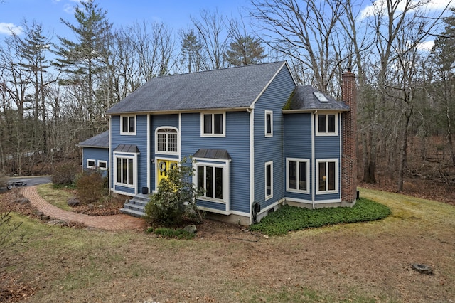 rear view of house with a lawn, roof with shingles, and a chimney