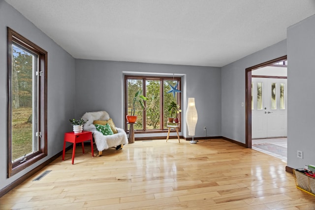 living area with wood-type flooring, baseboards, and visible vents