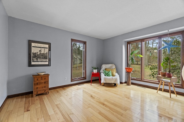 living area featuring baseboards, visible vents, and hardwood / wood-style floors