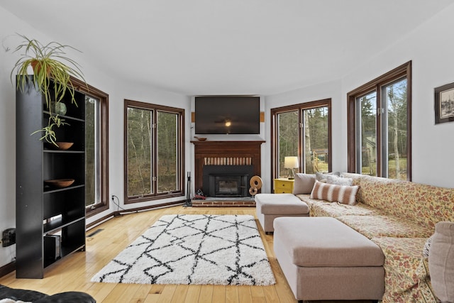 living area with a fireplace, a healthy amount of sunlight, and hardwood / wood-style floors