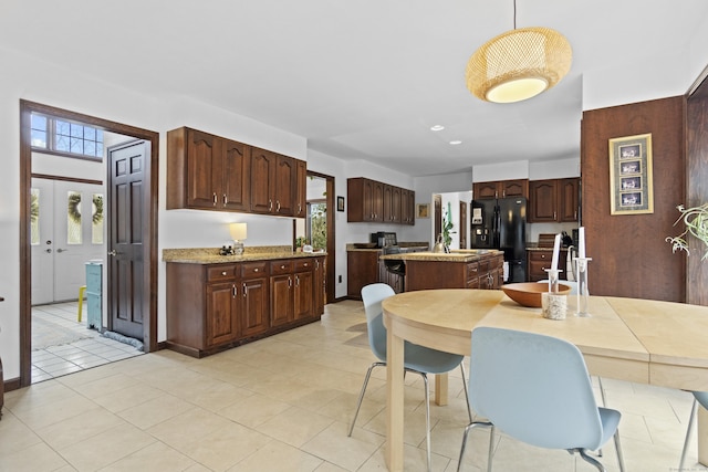 kitchen with dark brown cabinets, light countertops, a center island, freestanding refrigerator, and light tile patterned floors