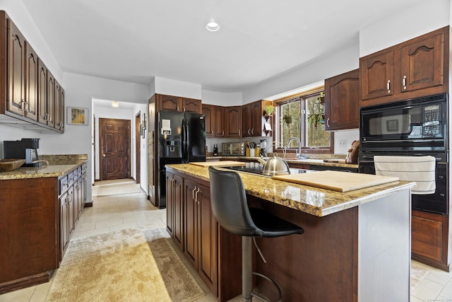 kitchen featuring a toaster, a kitchen island, light stone counters, a sink, and black appliances