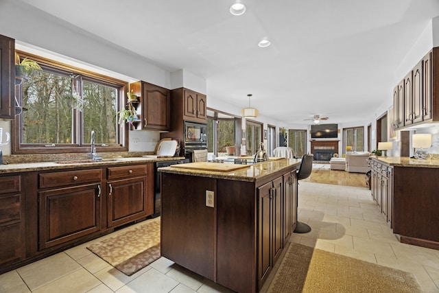 kitchen with a sink, a fireplace, dark brown cabinets, and open floor plan
