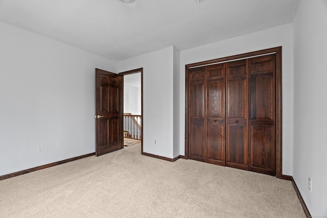 unfurnished bedroom featuring carpet flooring, baseboards, and a closet