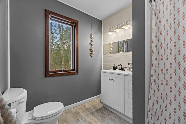 full bath with a shower with curtain, wood finished floors, vanity, baseboards, and toilet