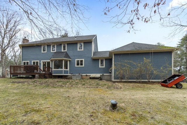 rear view of property featuring a chimney, a shingled roof, a yard, and a deck