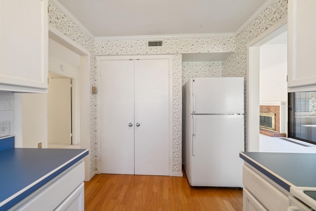 917 Heritage Vlg Unit B, Southbury, CT 06488 - kitchen featuring freestanding refrigerator, ornamental molding, light wood-style floors, white cabinetry, and wallpapered walls