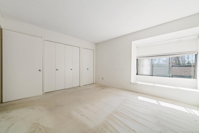917 Heritage Vlg Unit B, Southbury, CT 06488 - unfurnished bedroom featuring multiple closets and light carpet