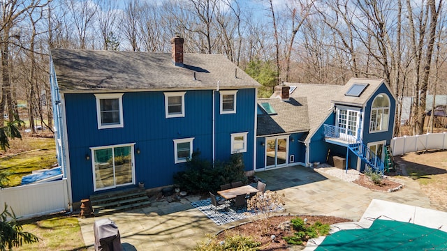 rear view of house featuring fence, entry steps, a patio, a chimney, and a shingled roof