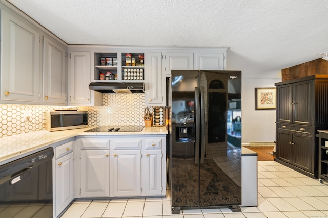 kitchen with a textured ceiling, light stone countertops, tasteful backsplash, under cabinet range hood, and black appliances