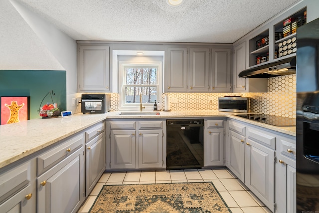 kitchen with gray cabinetry, black appliances, under cabinet range hood, and a sink