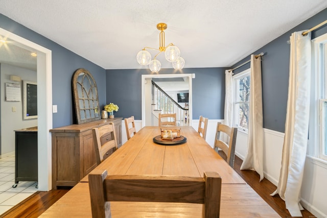 dining space with a textured ceiling, wood finished floors, and a chandelier