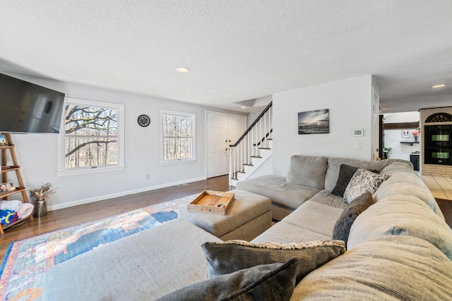 living area featuring baseboards, stairs, a textured ceiling, and wood finished floors
