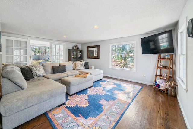 living room with plenty of natural light, dark wood-type flooring, baseboards, and a textured ceiling