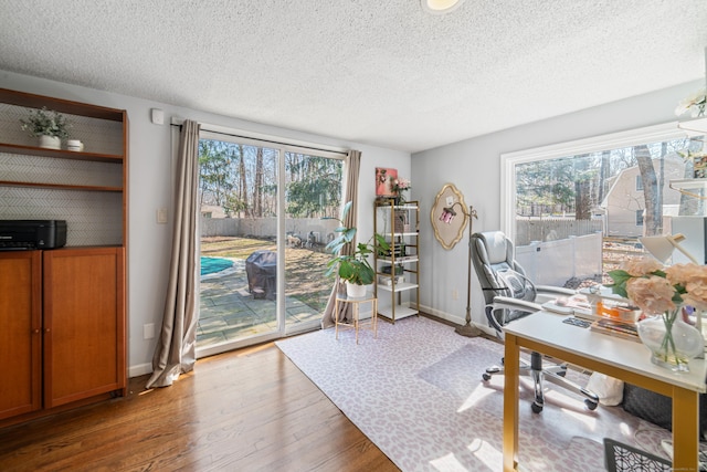 office featuring a textured ceiling, wood finished floors, and a healthy amount of sunlight